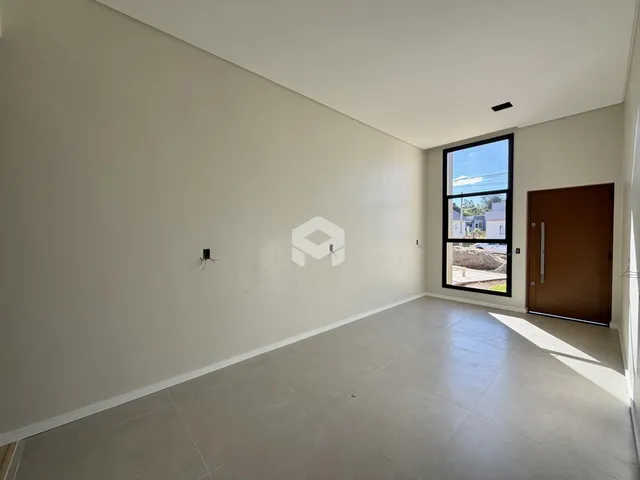Foto de um ambiente interno vazio com paredes brancas e piso claro.