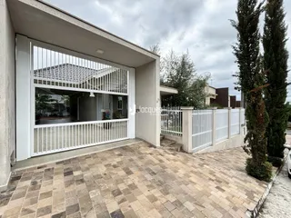 Fachada de casa com área externa pavimentada e cerca branca.