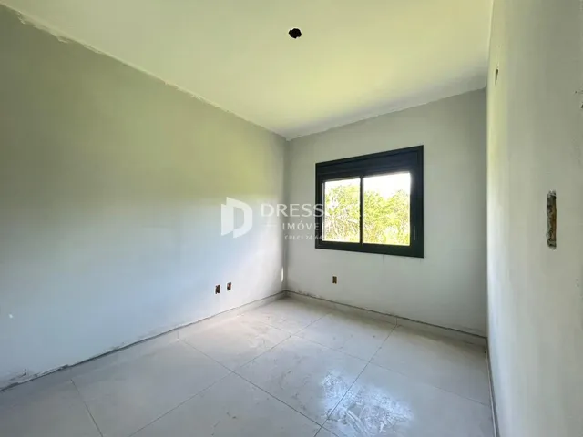 Vista interna de um corredor com paredes brancas e piso de cerâmica.
