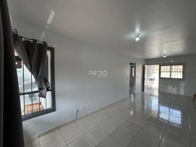 Foto do interior de uma sala com piso de cerâmica e uma grande janela.