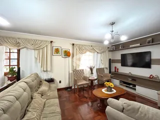 Sala de estar com sofá e janelas com cortinas claras.