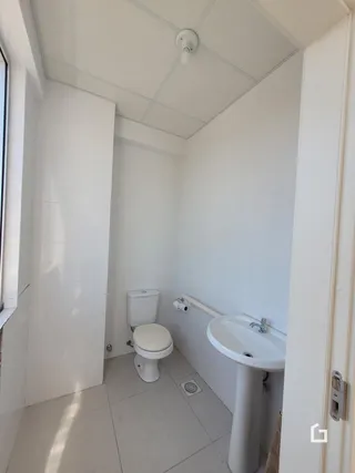 Foto interna de um banheiro com piso claro e louças brancas.