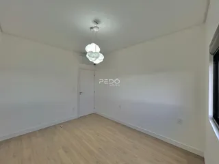Ambiente interno de uma sala com piso de madeira clara e paredes brancas.