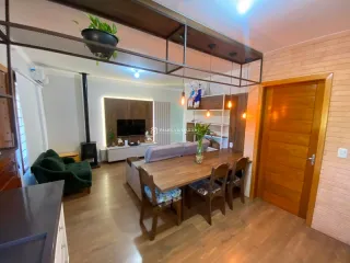 Sala de estar com mesa de madeira e sofá em ambiente com pé direito alto.