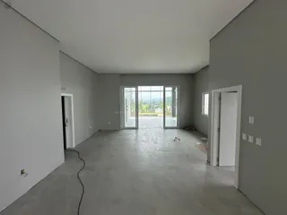 Ambiente interno amplo e vazio com piso de concreto e portas de vidro voltadas para o exterior.