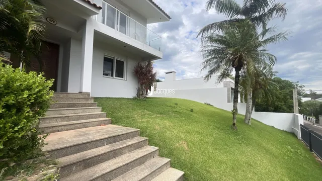 Fachada de uma casa branca com jardim gramado e escadaria.