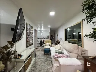 Sala de estar iluminada com sofá e televisão em um imóvel no Brasil.