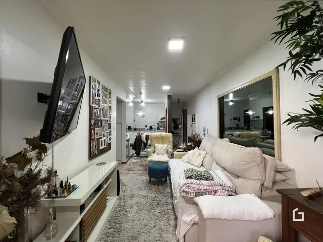 Sala de estar iluminada com sofá e televisão em um imóvel no Brasil.
