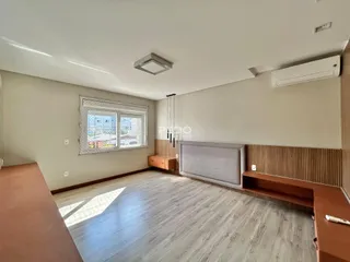 Quarto com piso de madeira clara e janela bem iluminada.