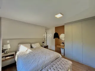 Quarto com cama e guarda-roupas em ambiente claro.