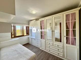 Quarto com cama e armário branco em um ambiente bem iluminado.