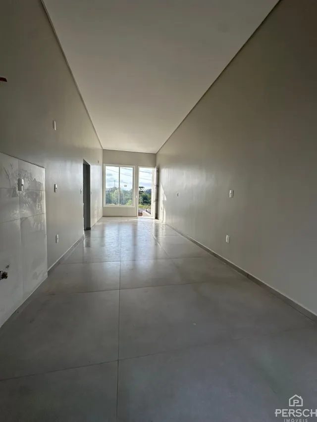 Foto de um corredor interno com paredes brancas e piso claro.