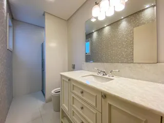 Banheiro com bancada de mármore clara e armários brancos em um ambiente bem iluminado.
