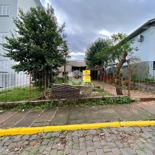 Vista externa de uma propriedade com árvores e cerca no quintal.