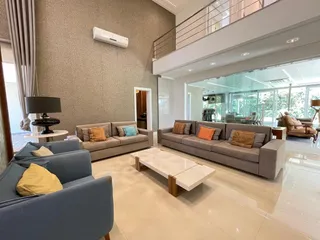 Sala de estar moderna com sofás cinzas e piso claro, com vista para a área externa.