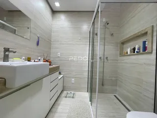 Interior de um banheiro com revestimento de cerâmica e box de vidro.
