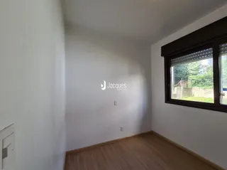 Interior de uma sala com piso de madeira e parede branca.