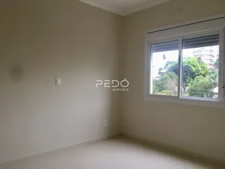 Ambiente interno de uma sala com paredes brancas e janela.