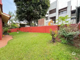Vista externa de um terreno com gramado e muro de tijolos vermelhos.