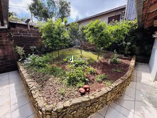 Jardim cercado por muro de pedra com vegetação exuberante.