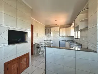 Interior de uma cozinha com revestimento de cerâmica e armários brancos.