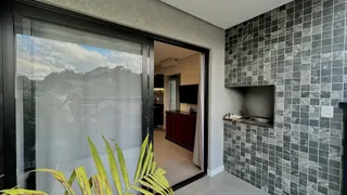 Vista da sala de estar com parede de azulejos escuros e porta de vidro.