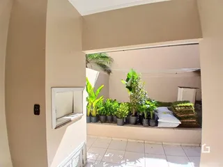 Vista de um corredor interno com jardim ao fundo.