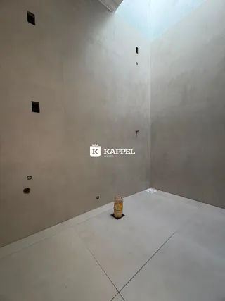Foto de um ambiente interno vazio com paredes brancas e piso claro.