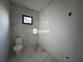 Banheiro com revestimento de mármore nas paredes e piso de cerâmica.