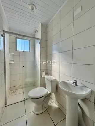 Foto de um banheiro com azulejos brancos e louças sanitárias.