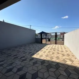 Uma área externa pavimentada com lajotas cinzas.