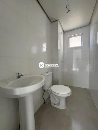 Banheiro com pia e vaso sanitário revestido em azulejos brancos.