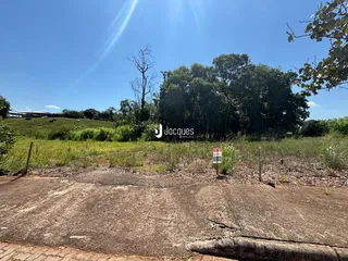 Vista de uma área de terreno gramado com vegetação ao fundo.