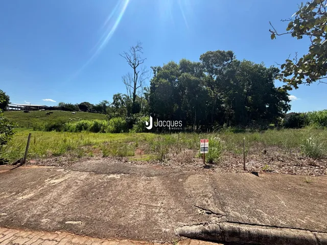 Vista de uma área de terreno gramado com vegetação ao fundo.