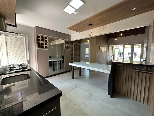 Vista de uma cozinha moderna com bancada escura e piso claro.
