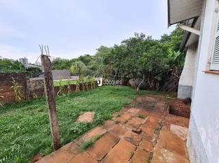 Vista externa de um jardim com caminho de tijolos e vegetação densa.