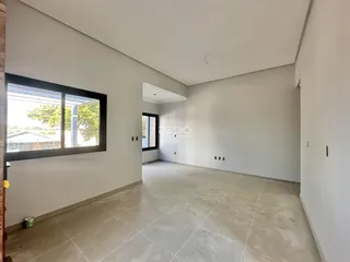 Interior de uma sala com paredes brancas e piso de concreto claro.