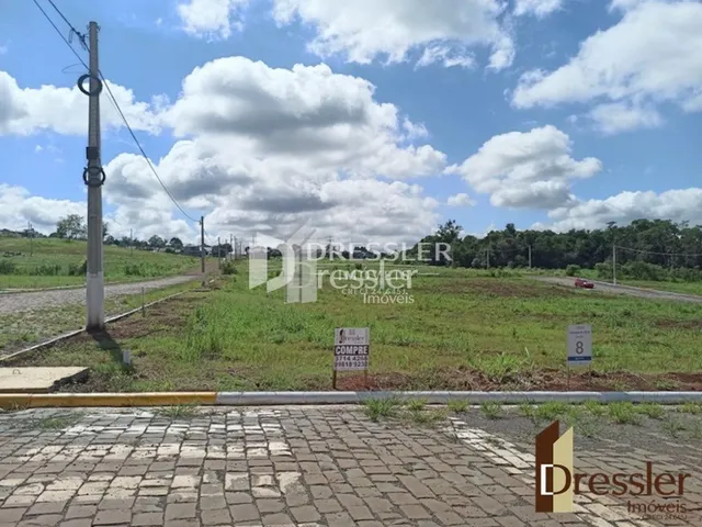 Vista externa de um lote com pavimento e vegetação ao lado de uma rua.
