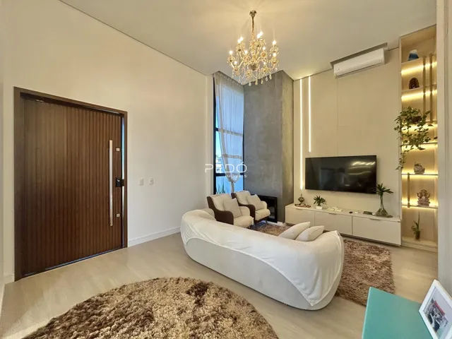 Sala de estar ampla com piso de madeira clara e sofá branco.