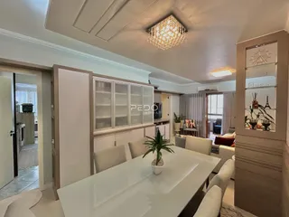 Uma sala de estar com armários brancos e móveis de madeira clara.