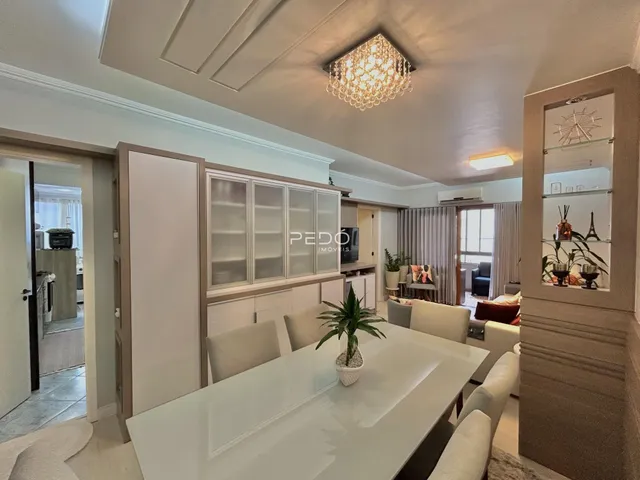 Uma sala de estar com armários brancos e móveis de madeira clara.