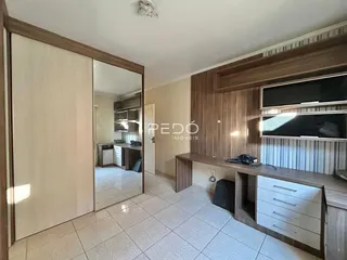 A sala de estar exibe um ambiente com piso de cerâmica e painéis de madeira.