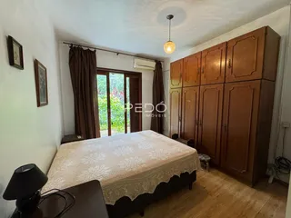 Quarto com armários de madeira e vista para o exterior.