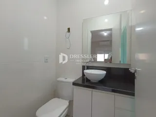 Interior de um banheiro com revestimento branco e bancada escura.
