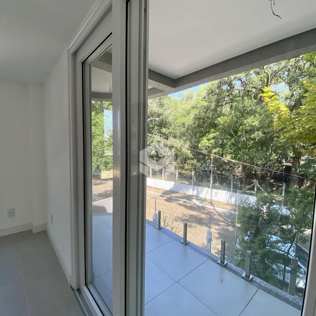 Ambiente interno com vista para a área externa arborizada.