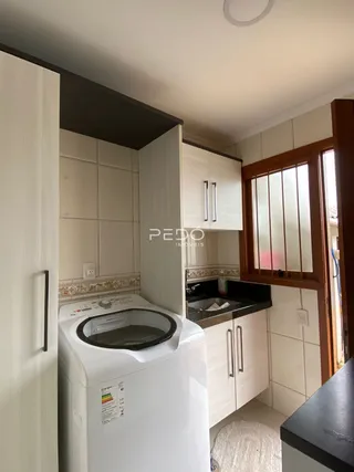 Interior da cozinha com armários brancos e máquina de lavar roupa.