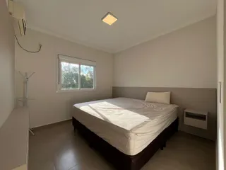 Quarto com cama de casal e janela iluminada.