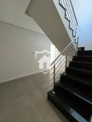 Hall de entrada com escadas e parede clara.