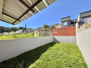 Vista externa de um quintal com gramado e muros de vedação.