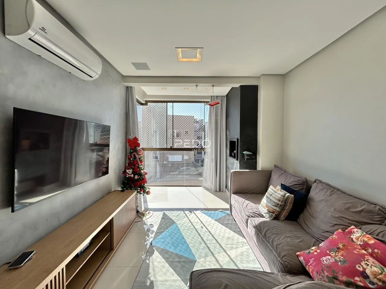 Sala de estar com sofá e televisão em um apartamento no Brasil.